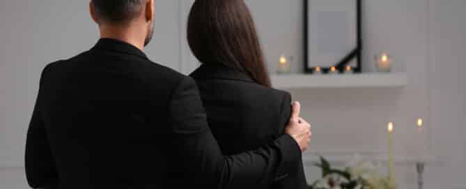 Couple mourning indoors, back view and space for text. Funeral ceremony