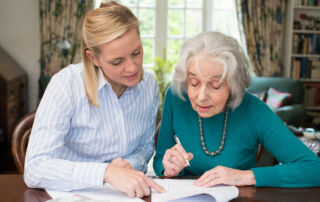 Woman Helping Senior Neighbor With Paperwork