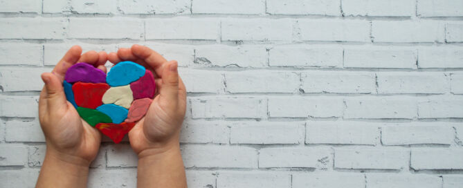 Child's hands holding a heart on white background with text space. World autism awareness day.